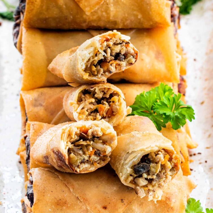 a bunch of freshly made spring rolls stacked on a serving platter.