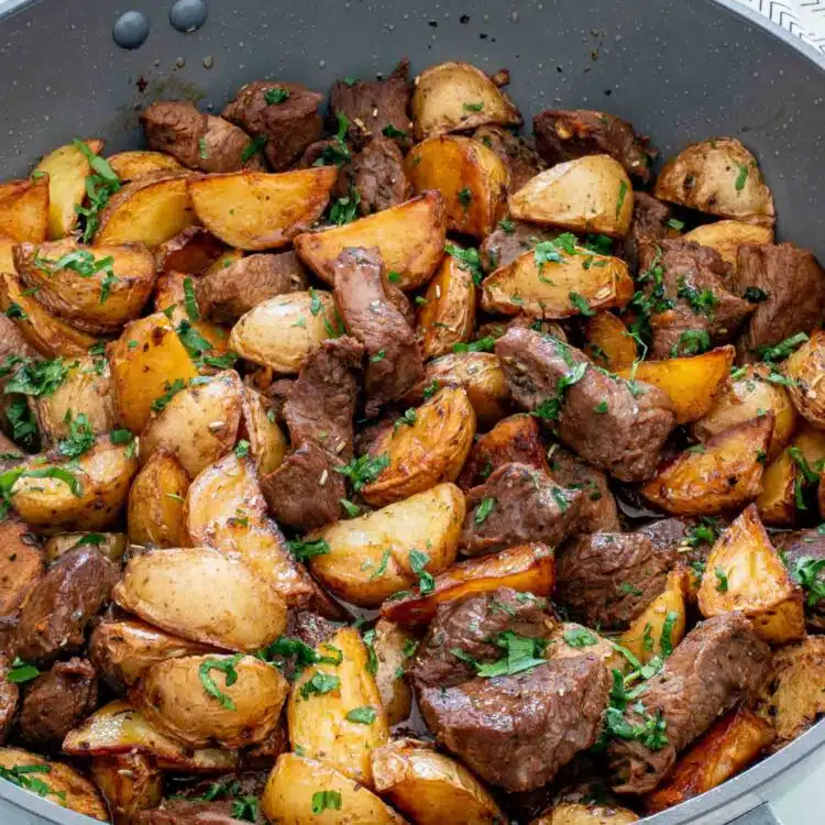 freshly made garlic butter steak and potatoes in a skillet.